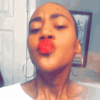 a woman wearing hoop earrings is blowing a kiss .