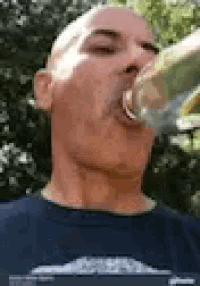 a man in a blue shirt is drinking from a bottle .