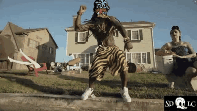 a man wearing zebra print shorts is dancing in front of a house .