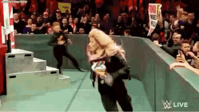 a woman is dancing in front of a crowd while holding a sign .