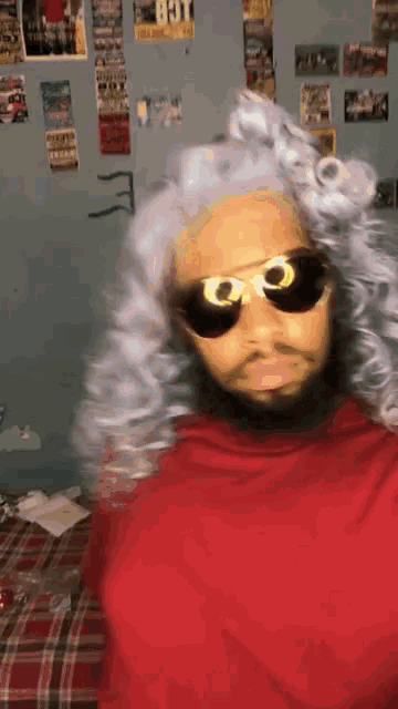 a man wearing sunglasses and a wig has the letter e on his shirt