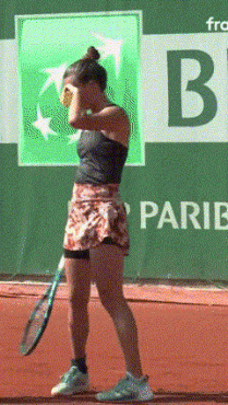 a woman is holding a tennis racquet in front of a b parib banner