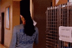 a woman wearing a shirt that says fire department is walking down a hallway