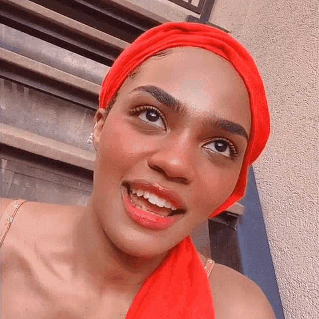 a woman wearing a red head scarf is smiling for the camera