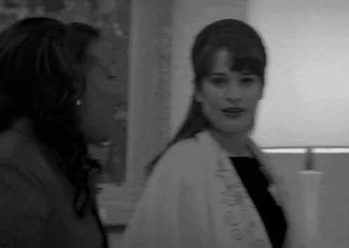 a black and white photo of two women with one wearing a white jacket