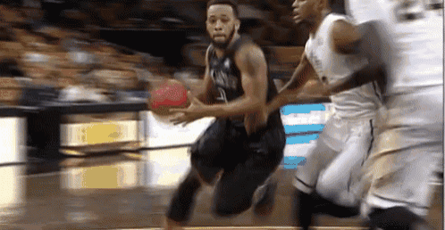 a basketball player is dribbling a ball while another player tries to stop him