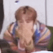 a person is sitting at a table with their hands on their face .