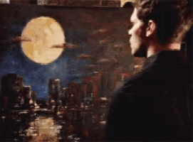 a man looking at a painting of a full moon