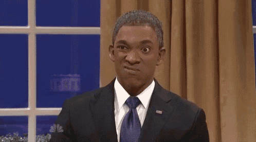 a man in a suit and tie is making a funny face while making a speech .