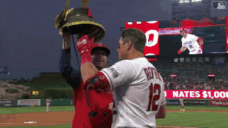 a baseball player with the number 12 on his jersey holds up a bell