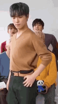 a young man is standing with his hands on his hips in front of a group of people .