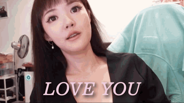 a woman in a black top says " love you " in pink letters