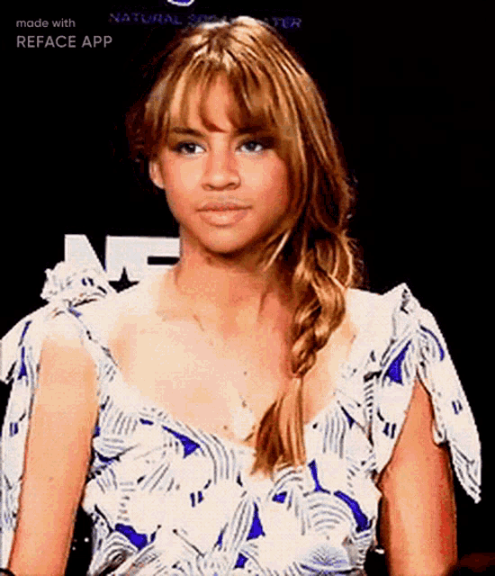 a woman in a blue and white floral dress is making a funny face .