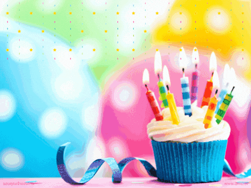 a birthday cupcake with candles and a ribbon on a table