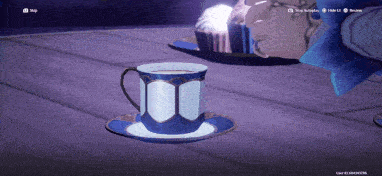 a blue and white cup on a saucer with a cupcake in the background