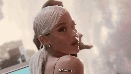 ariana grande is wearing a red dress and a ponytail and is looking over her shoulder .