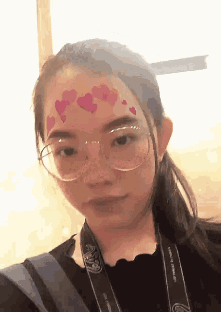 a girl with glasses and hearts on her face is wearing a camera strap that says canon