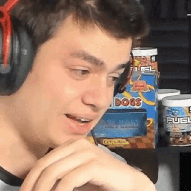 a young man wearing headphones is sitting in front of a table with boxes of fuel dogs .