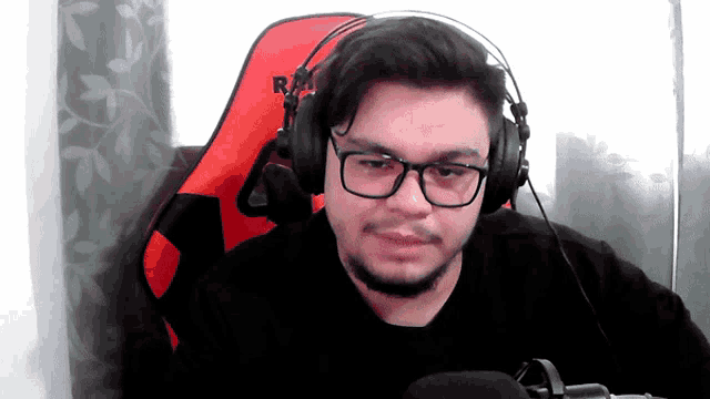 a man wearing glasses and headphones is sitting in a red chair that says rm