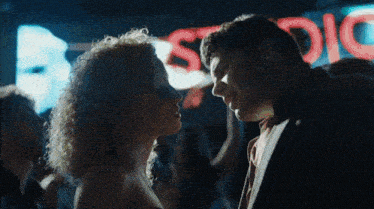 a man and a woman are kissing in front of a sign that says studio
