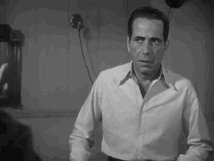 a man in a white shirt is standing in front of a mirror in a room .