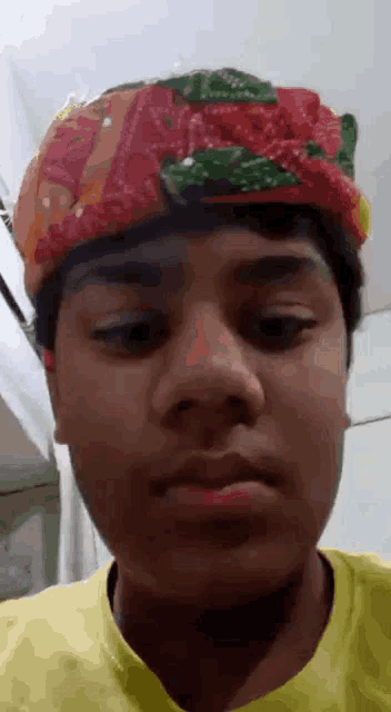 a young man wearing a turban on his head looks at the camera .