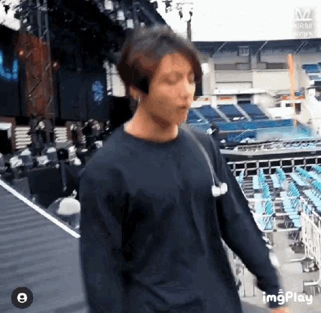 a young man wearing headphones is walking on a stage in a stadium .