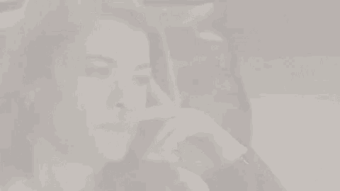 a woman is sitting on a couch with her hand on her hair and looking up .