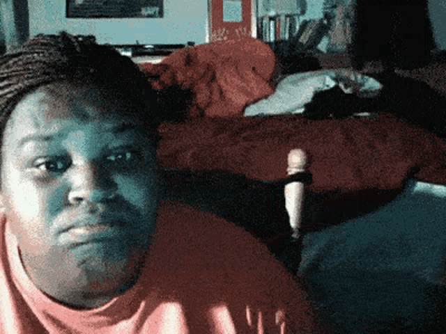 a woman sitting in front of a bed with a red comforter on it