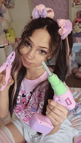 a girl in a pink shirt holds a toy drill that says " drill " on it