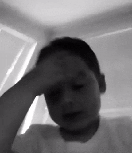 a black and white photo of a young boy holding his head .