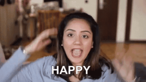 a woman is making a funny face and saying `` happy '' with her hands in the air .