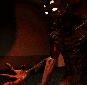 a dark room with a red wall and a statue