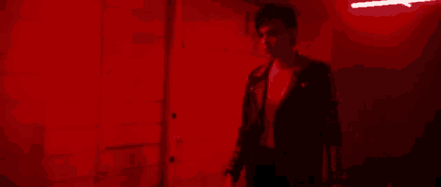 a man is standing in a dark room with red lights on the walls .
