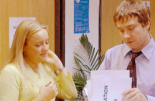 a man and a woman are looking at a piece of paper that says " ation " on it