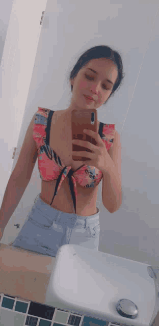 a woman in a bikini takes a selfie in front of a mirror