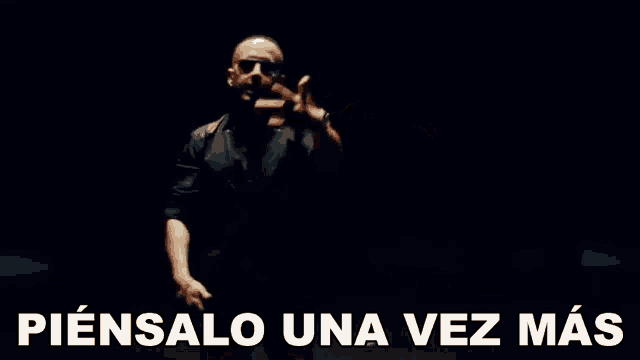 a man in a leather jacket is dancing in a dark room with the words piensalo una vez mas written on the bottom