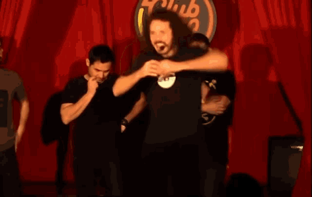 a group of men are standing on a stage in front of a sign that says club 99