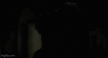a close up of a person 's face with a crow on their head in a dark room .