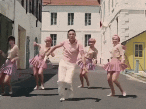 a man in a pink shirt and white pants is surrounded by women in pink skirts