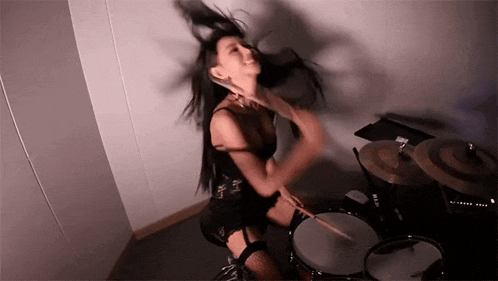 a woman is playing a drum set in a room