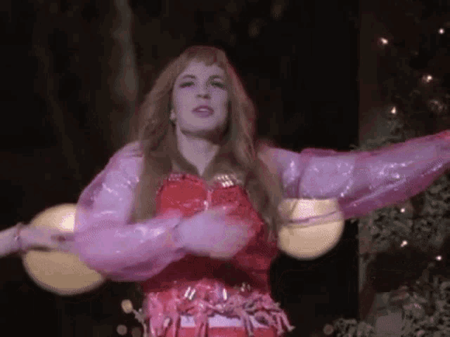 a woman in a red dress and purple sleeves is dancing .