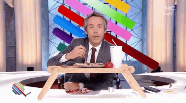 a man in a suit and tie is sitting at a table with a tray of food on it