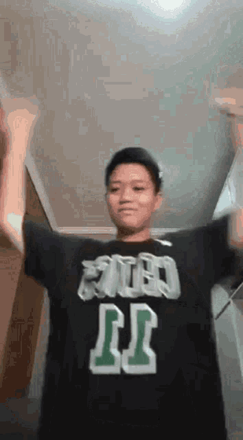 a young man wearing a black shirt with the number 11 on it is dancing .