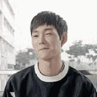 a young man wearing a black sweater is smiling and looking at the camera .