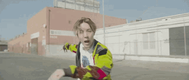 a man in a yellow jacket is riding a bicycle down a street .