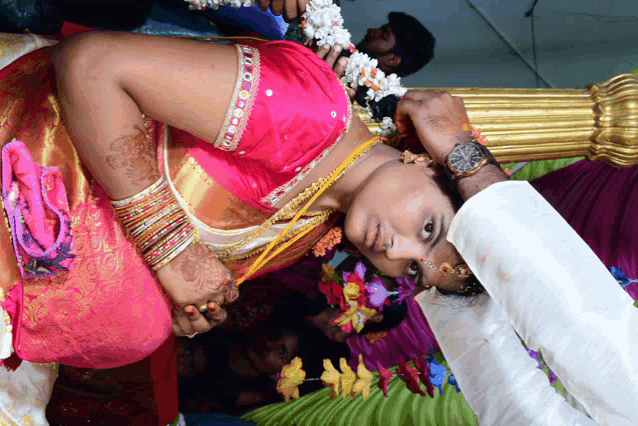 a woman in a pink and gold dress is laying on her back with a man wearing a watch on her wrist