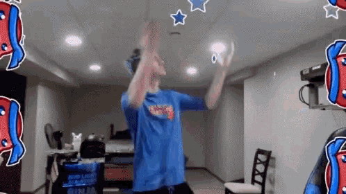 a man in a blue shirt is standing in a room with his arms in the air .