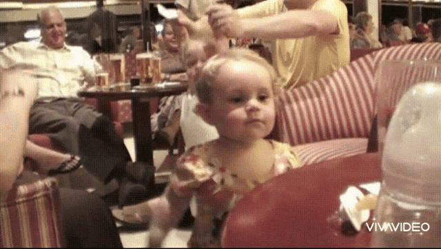 a baby is sitting at a table with a bottle of milk in front of her