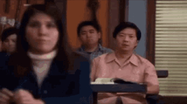 a group of people are sitting in a classroom and one of them is looking at the camera .
